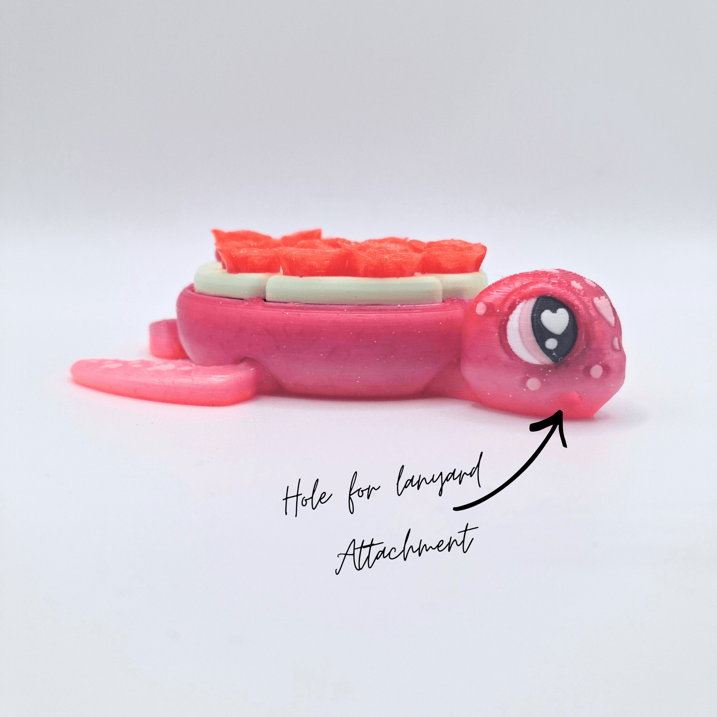 Pink toy turtle clicker with a hole for a lanyard attachment on a white background