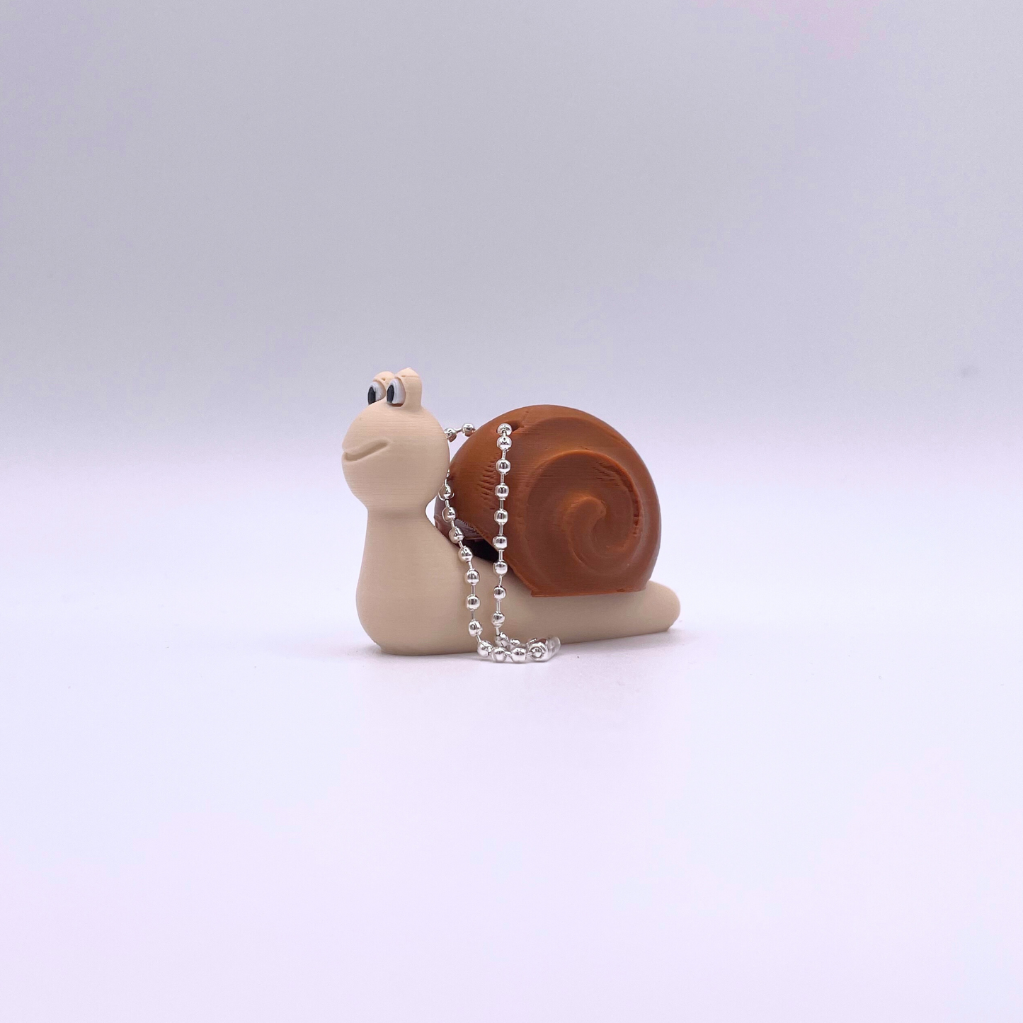 Snail clicker fidget toy in brown and beige with a ball chain, ASMR sensory toy for calming and relaxation.