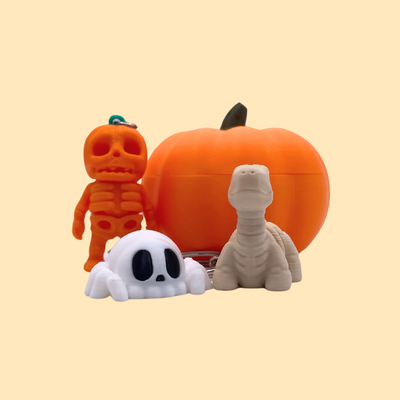 Pumpkin Bundle with storage container and 3 Halloween keyrings—ghost spider, skeleton brontosaurus, and pumpkin skeleton—unique festive gift set.