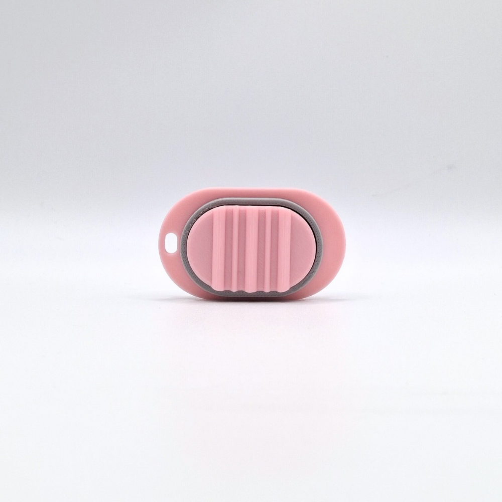 A small pink and grey oval-shaped accessory with a ribbed magnetic sensory tool for adults, photographed on a clean white studio background.