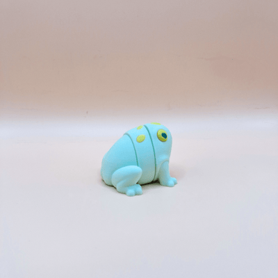 Small green frog figurine on a beige background